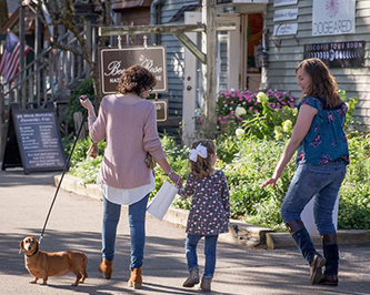 Women strolling through Olde Mistick Village with a dog on a leash