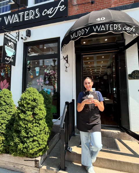 Barista stands in front of Muddy Waters Cafe